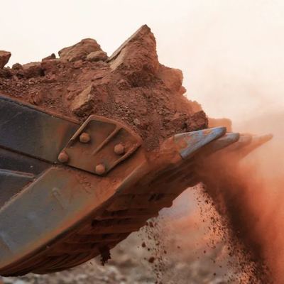 Excavator bucket unloading earth in a cloud of dust