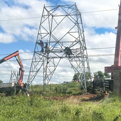 Workers harnessed on a steel transmission tower during erection