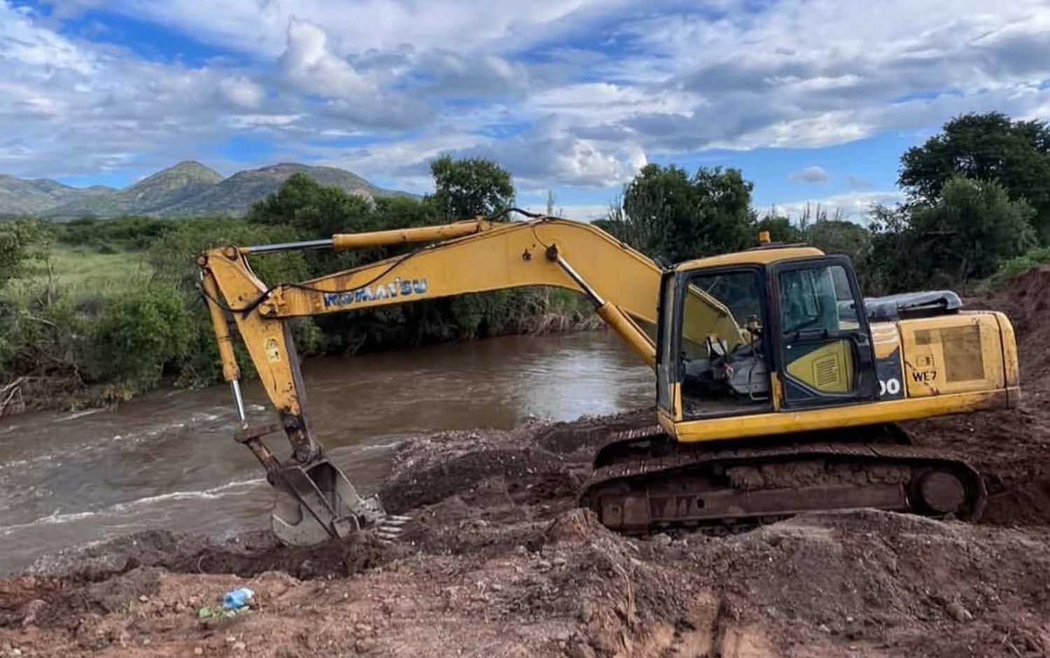 TMP Komatsu excavator carrying out river-crossing earthworks against a Limpopo mountain backdrop